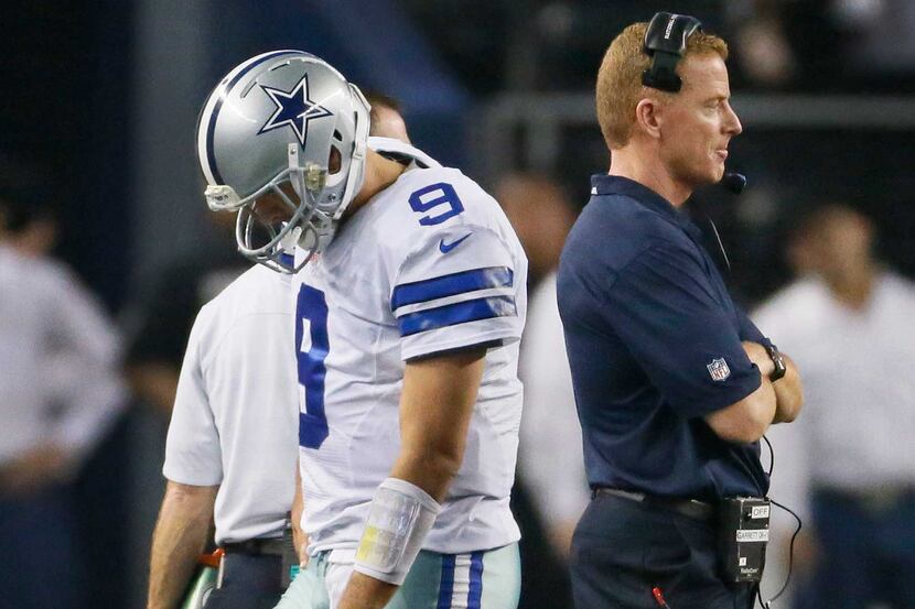 Cowboys quarterback Tony Romo walks past head coach Jason Garrett after throwing an...
