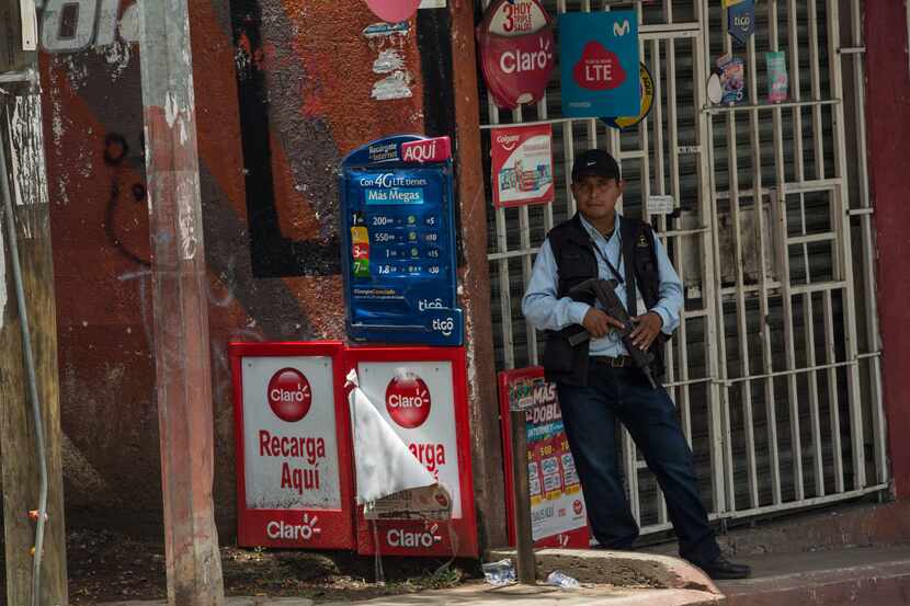 Oficial de policía en la Ciudad de Guatemala vigila la entrada a una tienda.