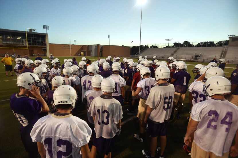Denton High School football go through warmup drills before sunrise on the first day of fall...