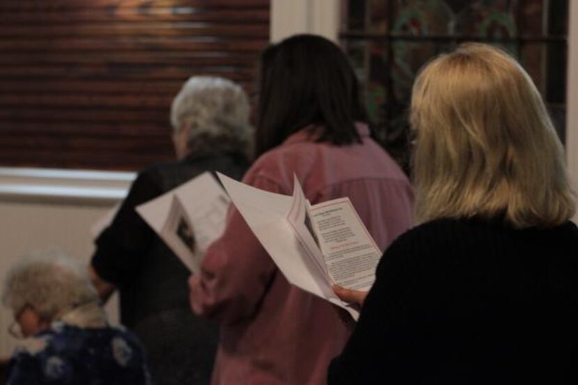 The stained glass windows of Sacred Heart Catholic Church’s chapel list names of families...