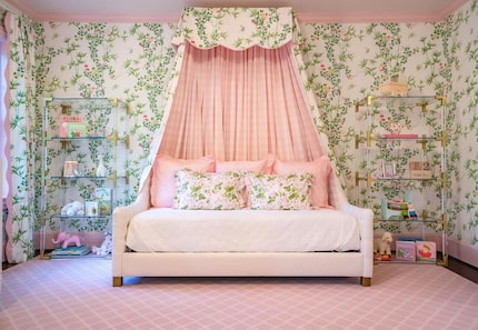 Pink daybed with gingham and floral curtain over it, with floral wallpaper and pink rug