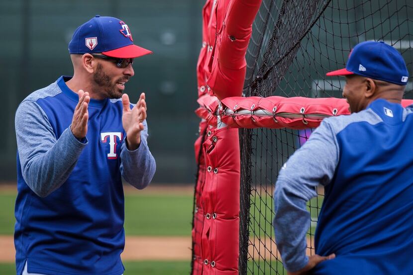 Texas Rangers manager Chris Woodward talks with third base coach Tony Beasley around the...