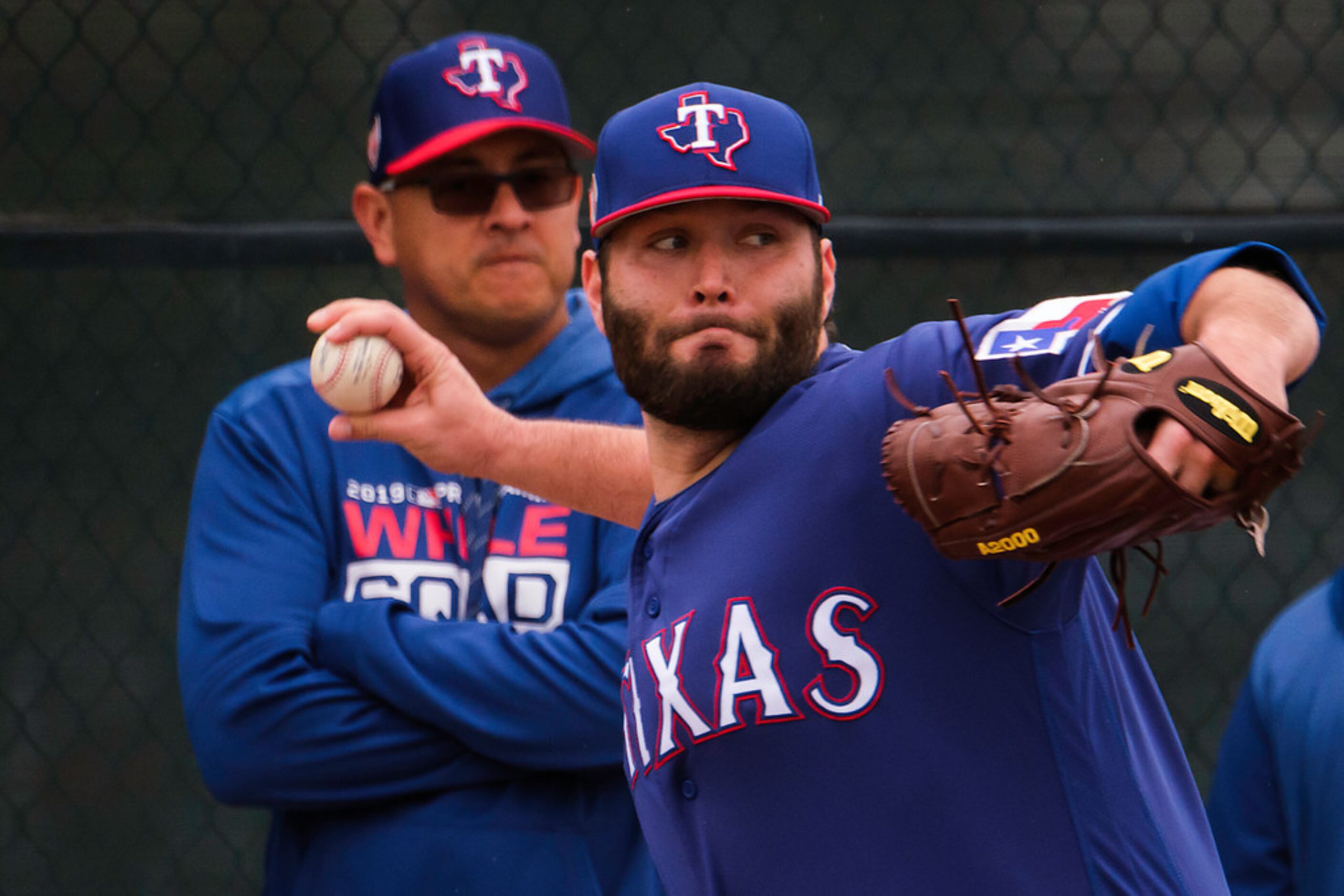 Texas Rangers pitcher Lance Lynn throws a bullpen session as pitching coach Julio Rangel...