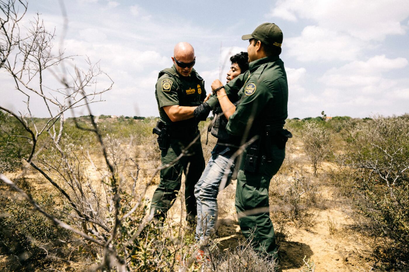 Border Patrol agents Michael Johnson (left) and Christian Salmon apprehend a Honduran...