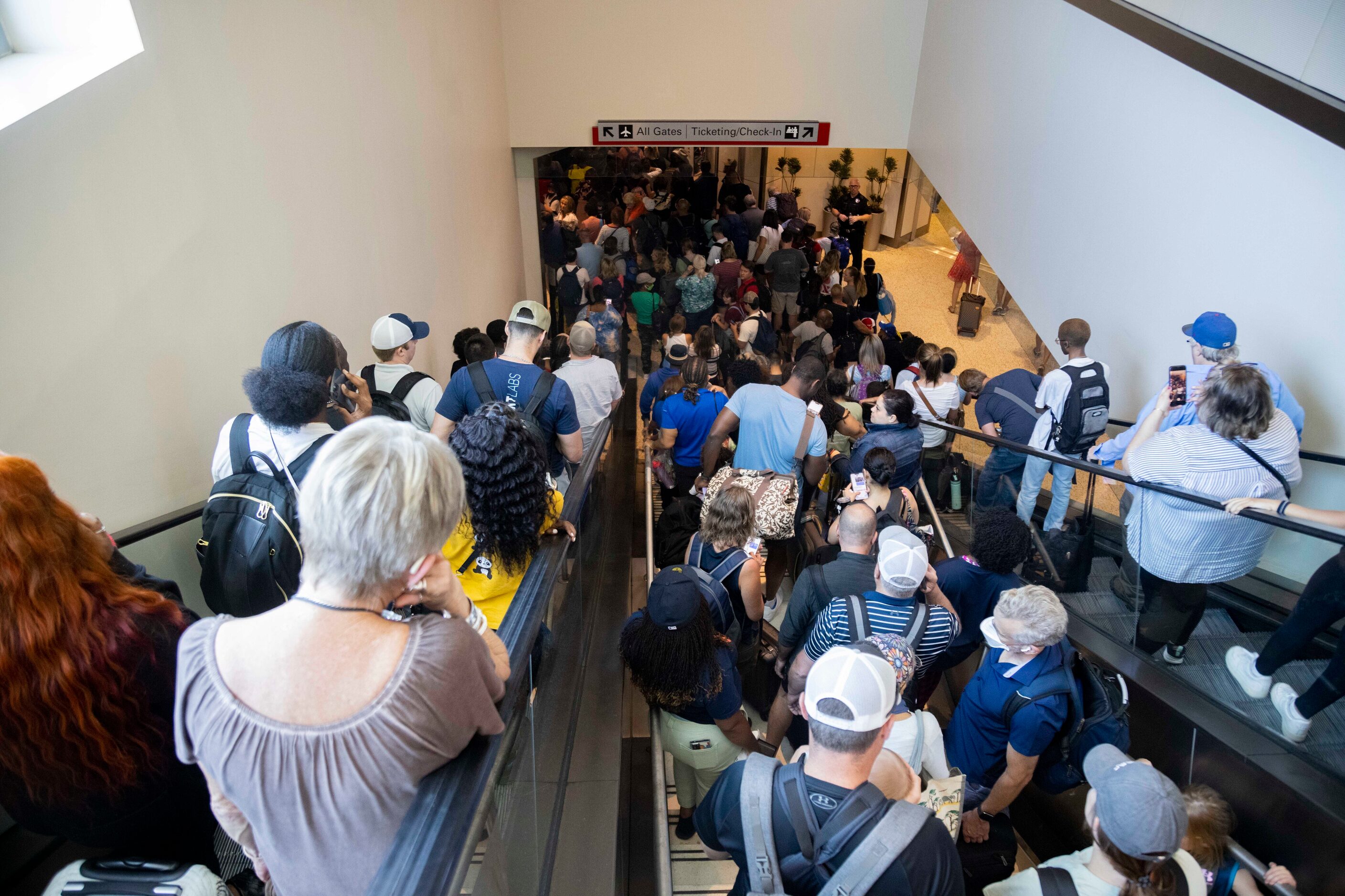 People wait in line to reenter the airport as Dallas police investigate reports of a...