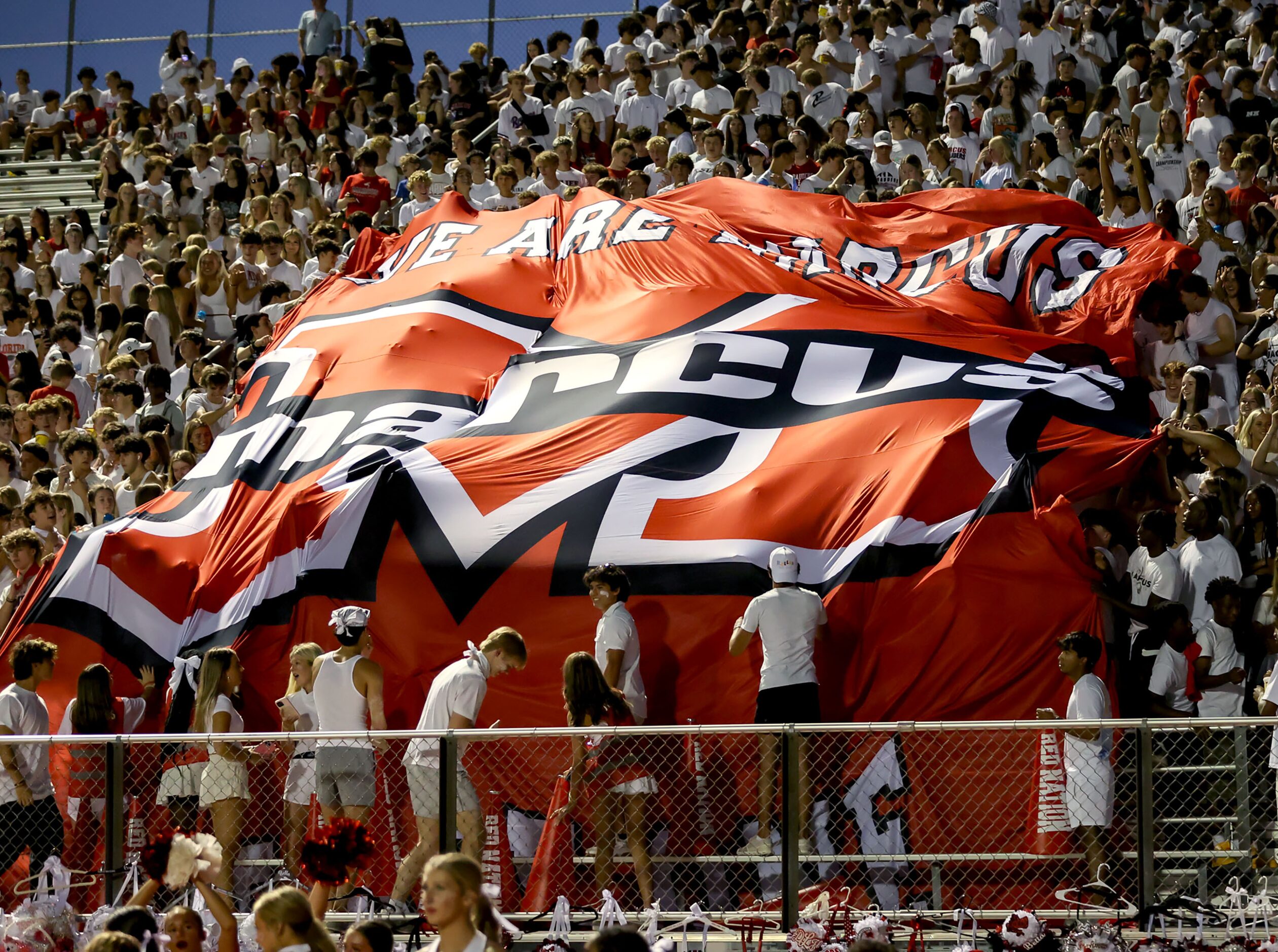 The Flower Mound Marcus students pull up a big banner after their team scored a touchdown...