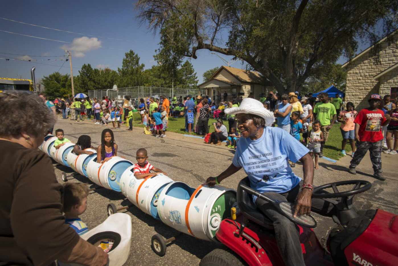 Bertha Carter pulls children in a makeshift train with her mower during a parade in...