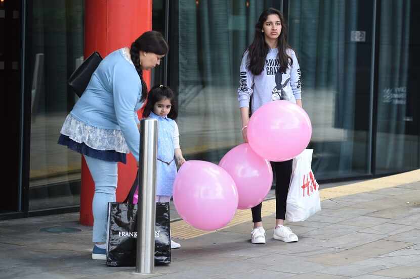 A woman (L) with two girls, one wearing a t-shirt of US singer Ariana Grande with balloons...