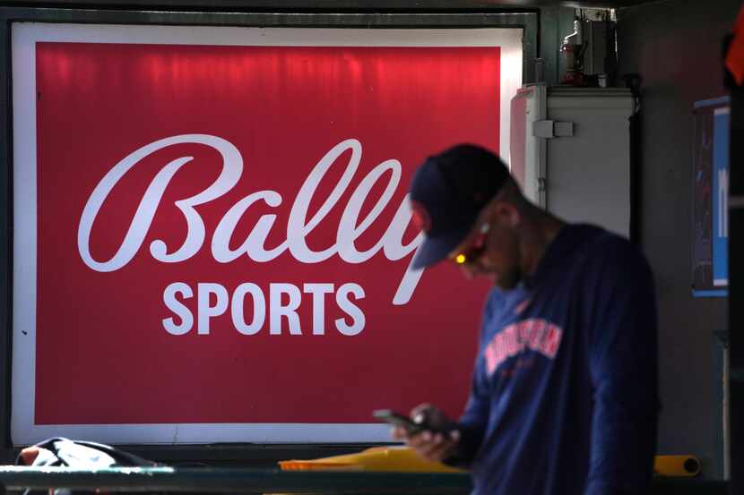 FILE - A member of the Houston Astros stands in the dugout in front of a Bally Sports sign...