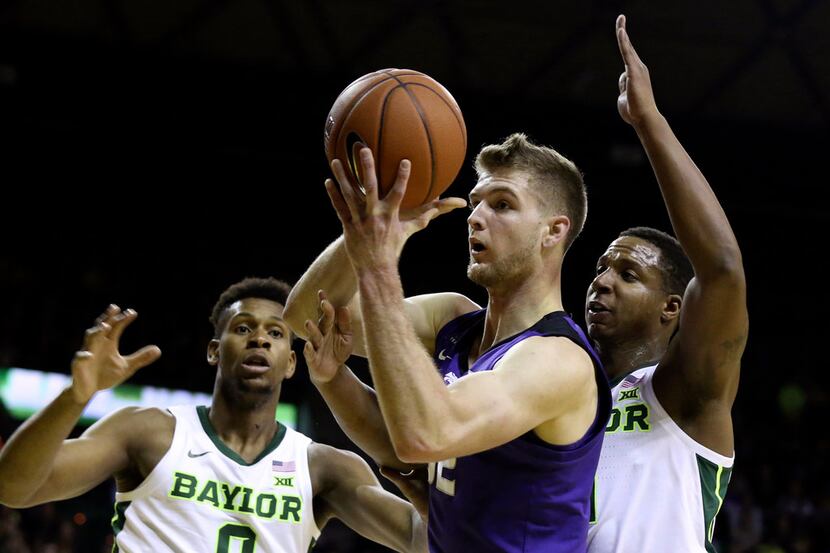 Kansas State forward Dean Wade, center, is guarded by Baylor guard Mark Vital, right, and...