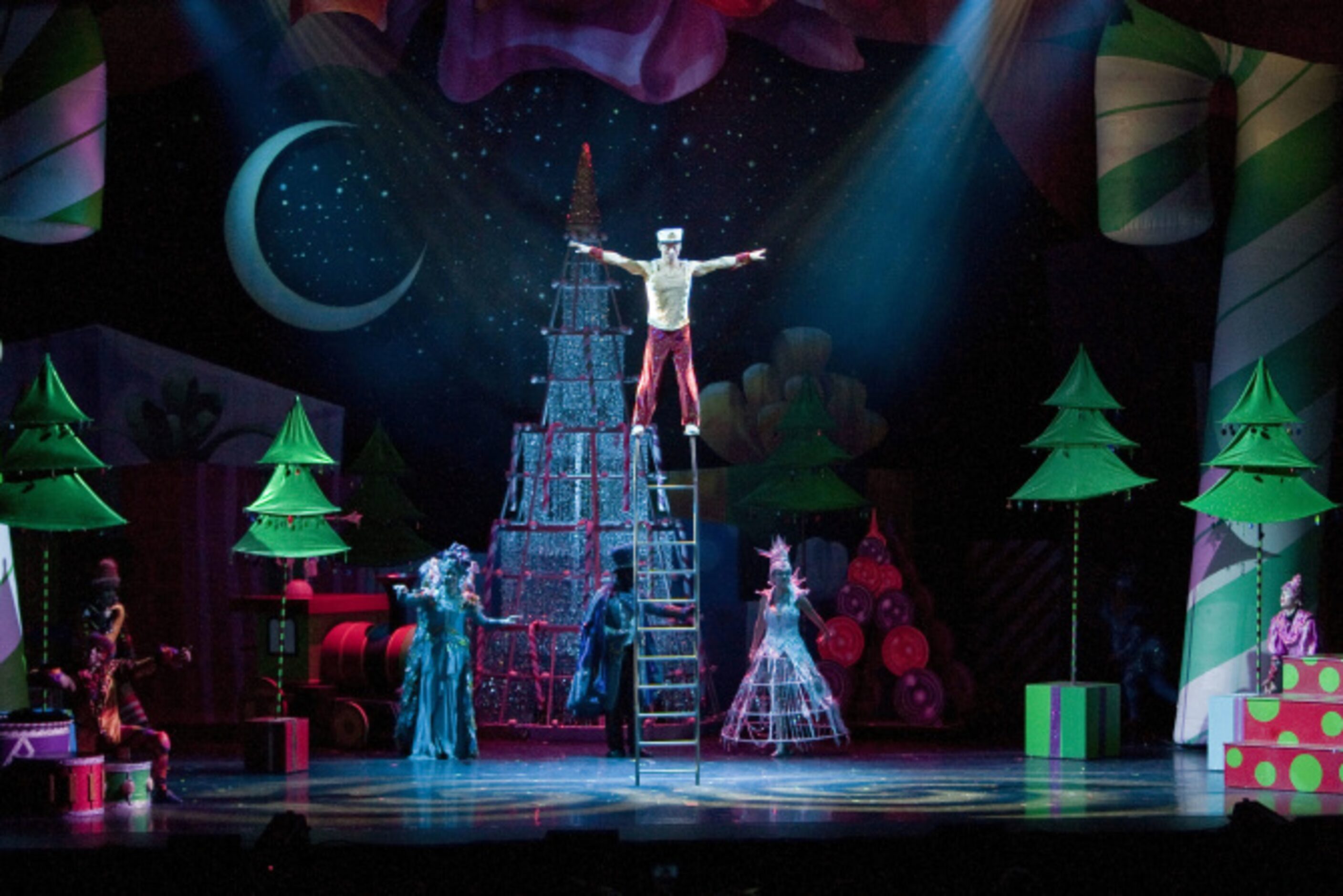 A performer acting as a toy solider balances on a free standing ladder during a performance...