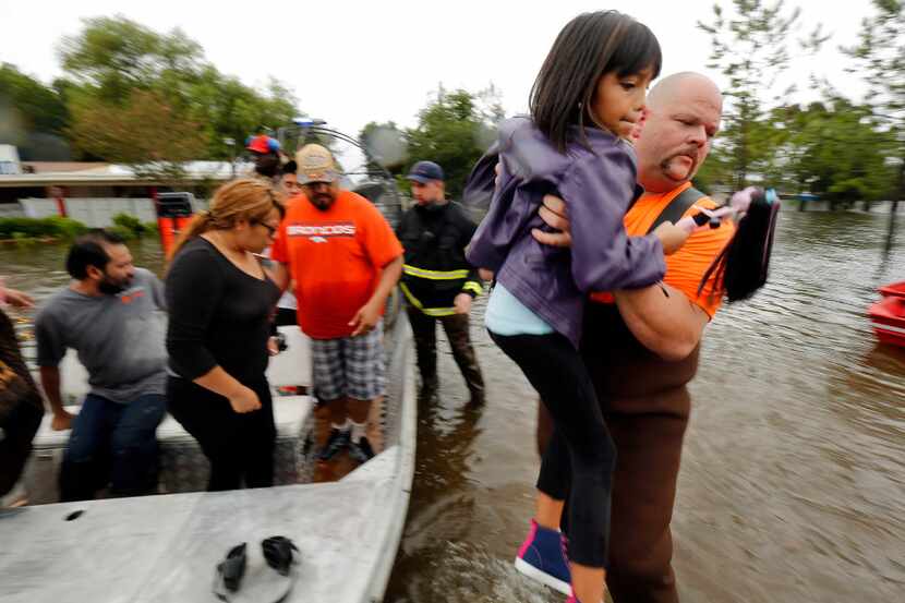 County Road 143 volunteer firefighter James Miller lifts 9-year-old Pearl Benitez from a...