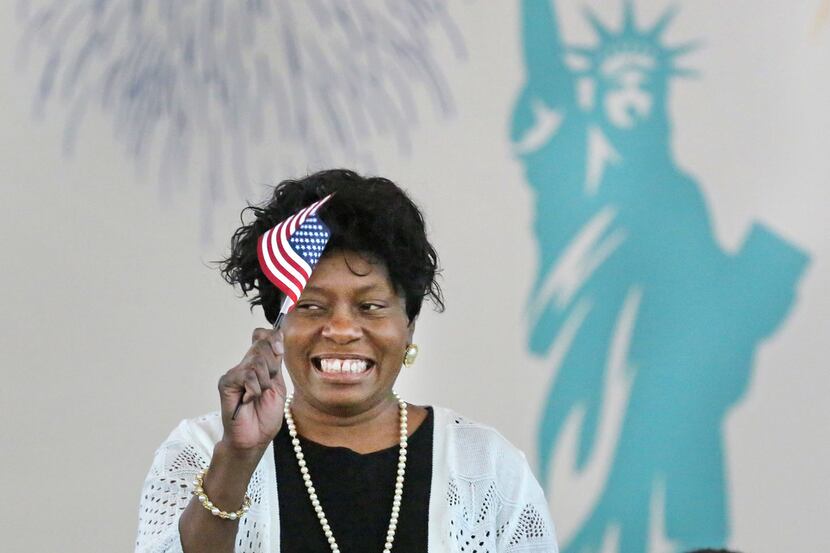 Elizabeth Evans, who is from Zambia, happily waves a miniature American flag as she becomes...