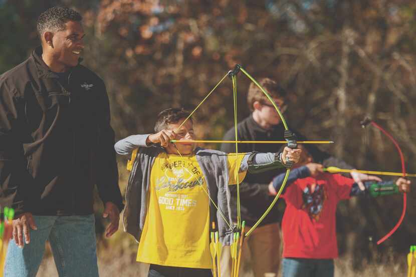 A group of scouts learns how to use a bow and arrow with their chaperones.