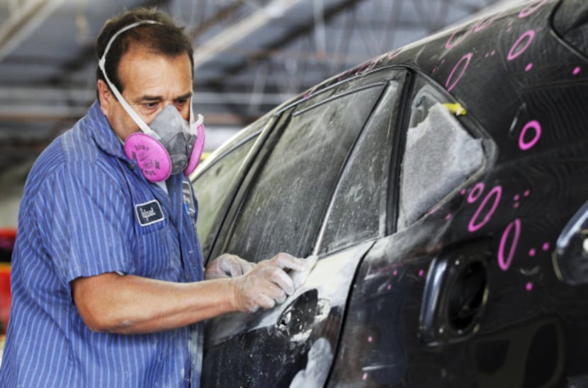 Rafael Trejo, a technician at the Service King in Lewisville, works on a hail-damaged car.