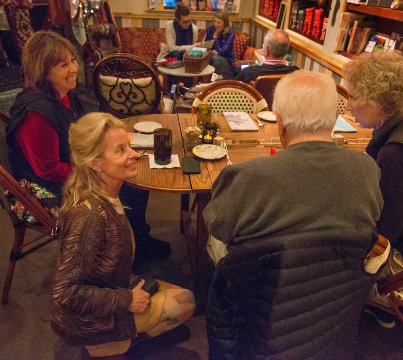 Hedda Dowd kneels to chat with a table of long-time regulars in her Inwood Village...