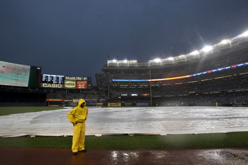 The field is covered with a tarp during a rain delay before a baseball game between the New...