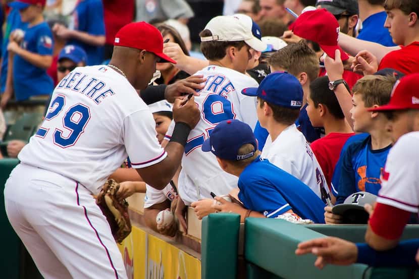 Texas Rangers third baseman Adrian Beltre autographs a fan's jersey bearing his number...