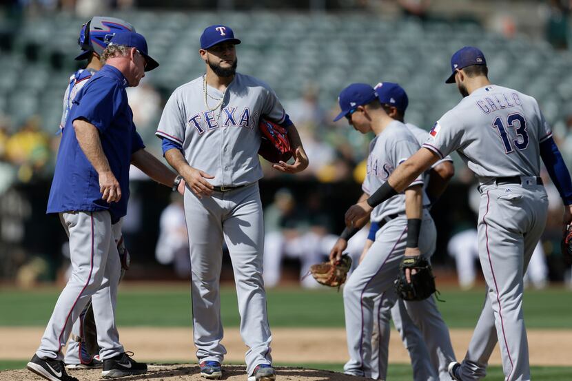 Texas Rangers pitcher Martin Perez, second from left, walks off the mound after being...