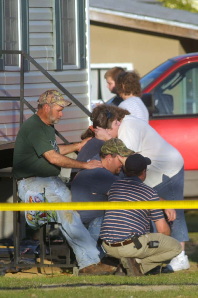 Relatives of victims in a shooting rampage comfort each other outside a home on March 10,...