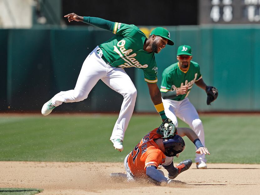 Oakland Athletics' Jurickson Profar, left, tags out Houston Astros' Derek Fisher in a...