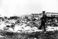 A Black man with a camera looks at the burned ruins in Tulsa's Greenwood District after the...