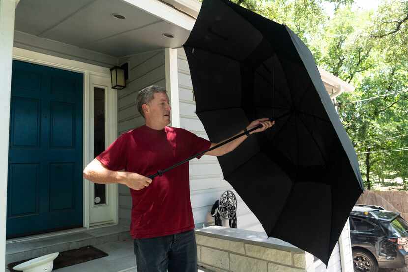 Travis Heights resident Eric Klein shows his new umbrella he bought to protect himself from...