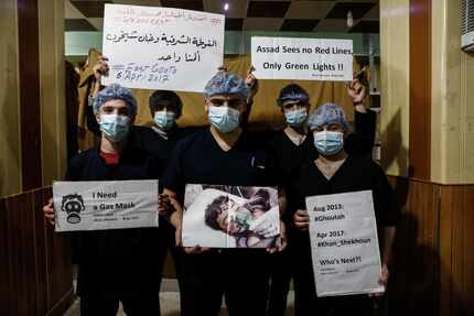 Medical staff at Damascus Countryside Specialised Hospital hold placards condemning a...