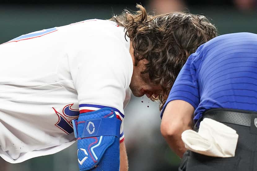 Texas Rangers outfielder Josh Smith is helped up by the Rangers’ medical staff after he was...