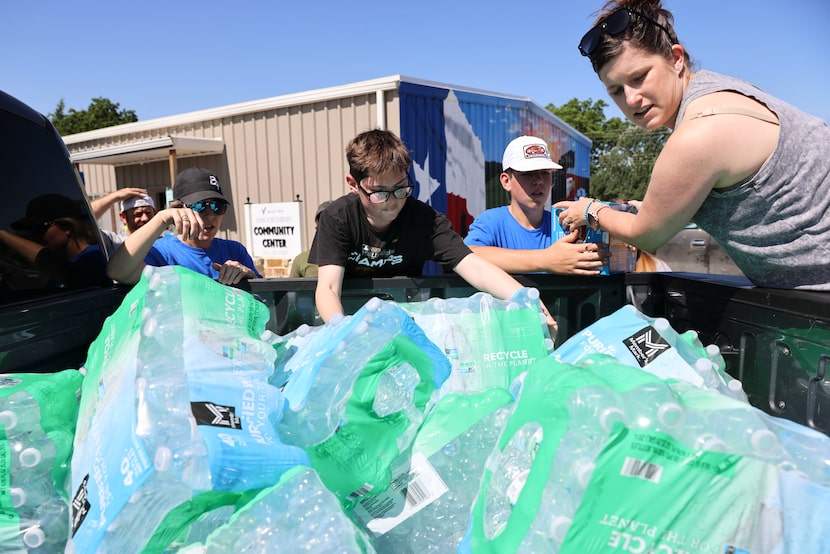 Jennifer Hurley (right) helps volunteers unload water bottles from her truck at John...