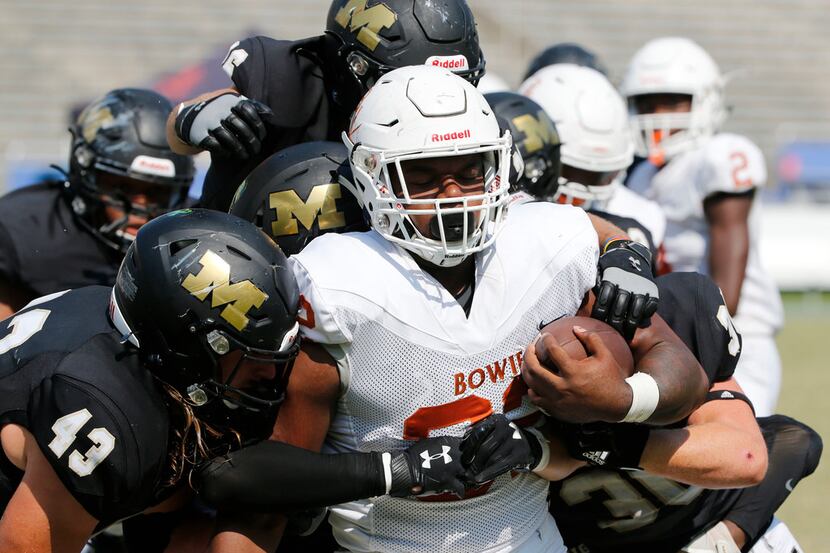 Mansfield defender Tyler Cole (43) and others gang tackle Arlington Bowie's Marsaillus Sims...