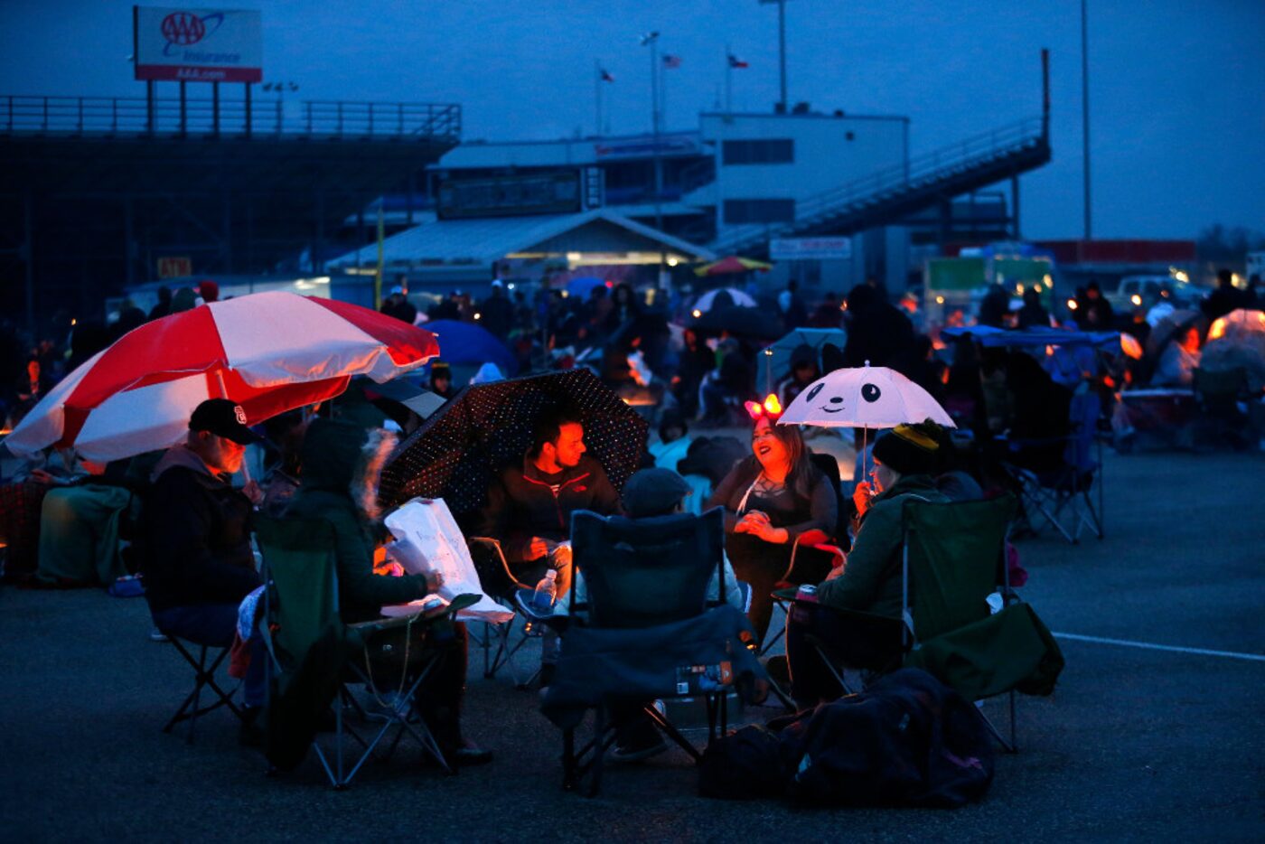 People take cover from the light rain and keep warm around a fire before lighting paper...