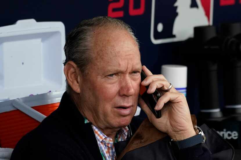 Houston Astros owner Jim Crane talks on the phone in the dugout before Game 4 of a baseball...