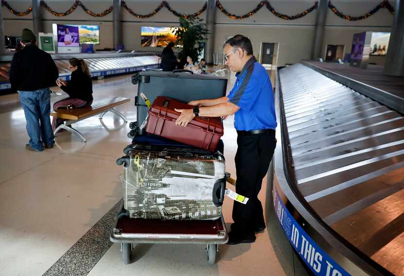 A Southwest Airlines employee collects luggage left on a carousel Friday as passenger...
