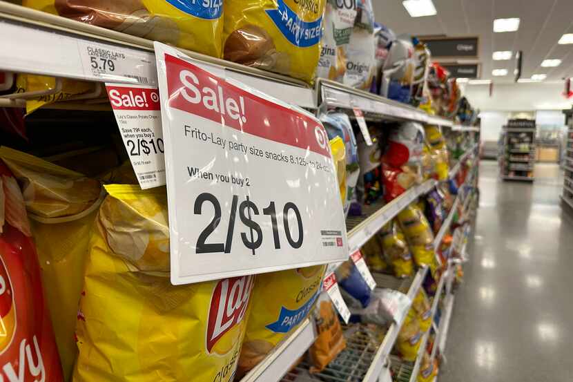 A sale sign hangs below a shelf of potato chips in a Target store last month. Two bags for...