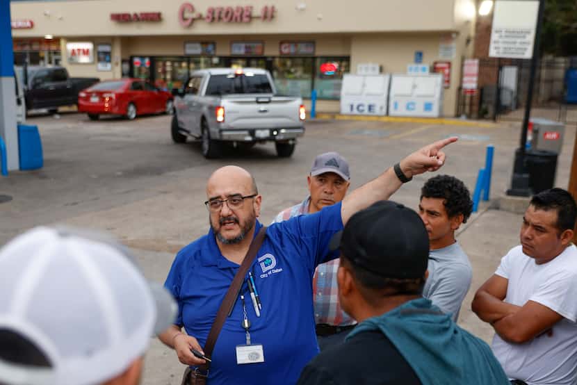Day labor Outreach Coordinator Alberto Ponce (center) speaks to day laborers as they for...
