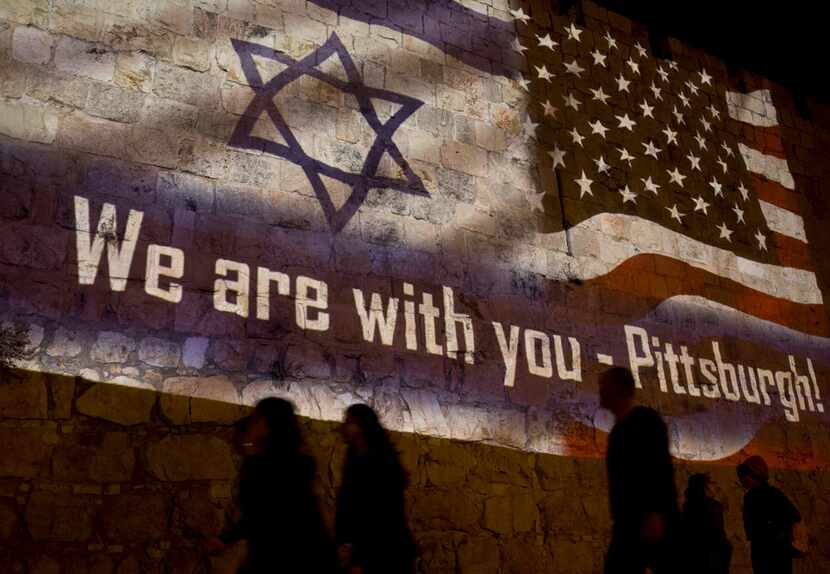 People walk past a projection on the Old City wall in Jerusalem on Oct. 28, 2018, in a...