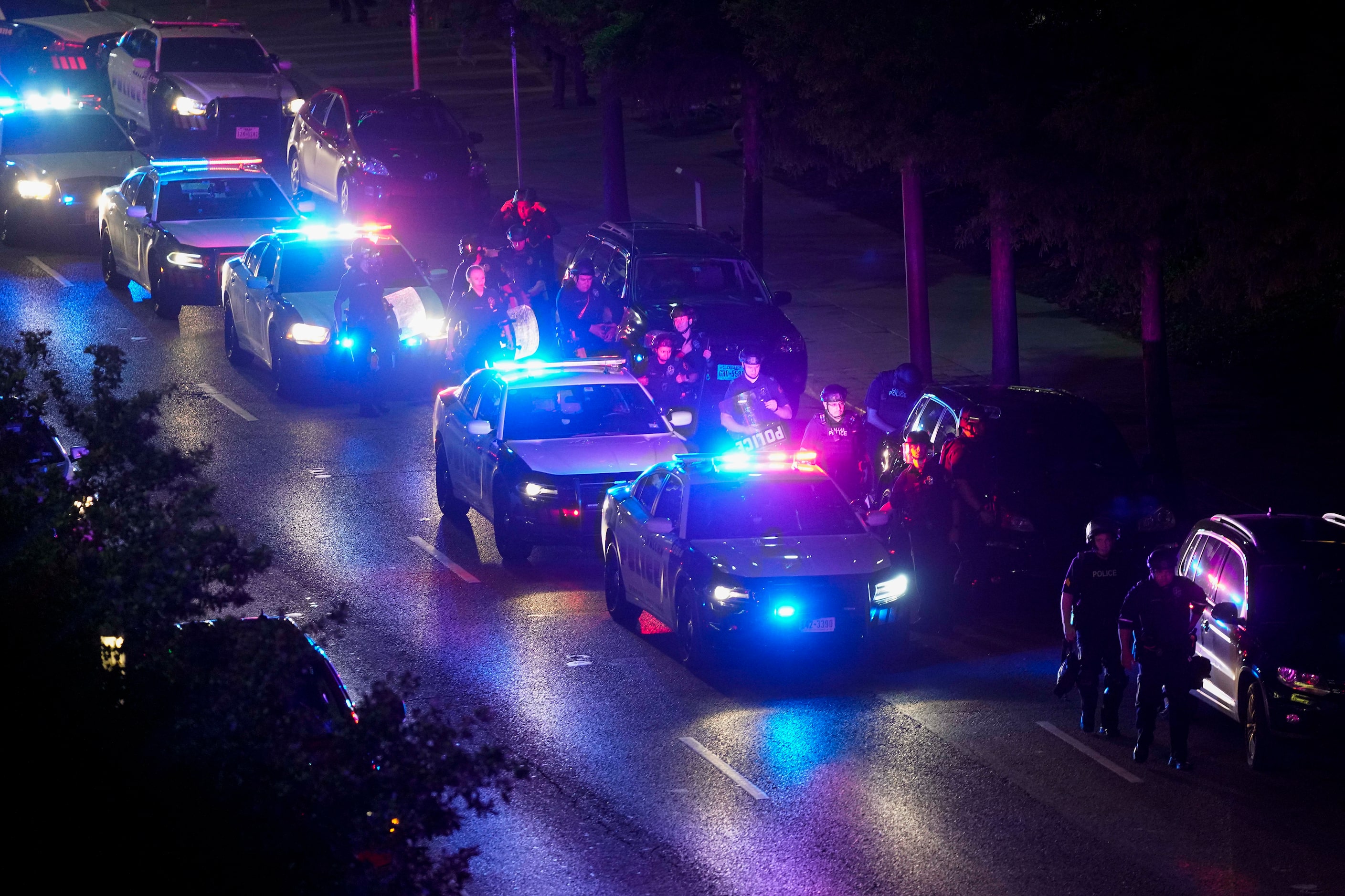 Dallas police move down Commerce Street as they go block by block working to clear groups of...