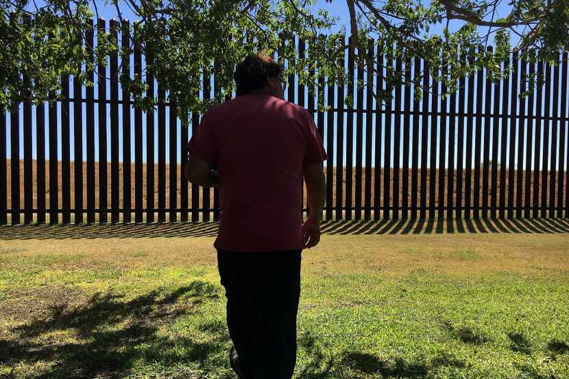 Jose Manuel Reyes walks along the border fence in his backyard in Brownsville.