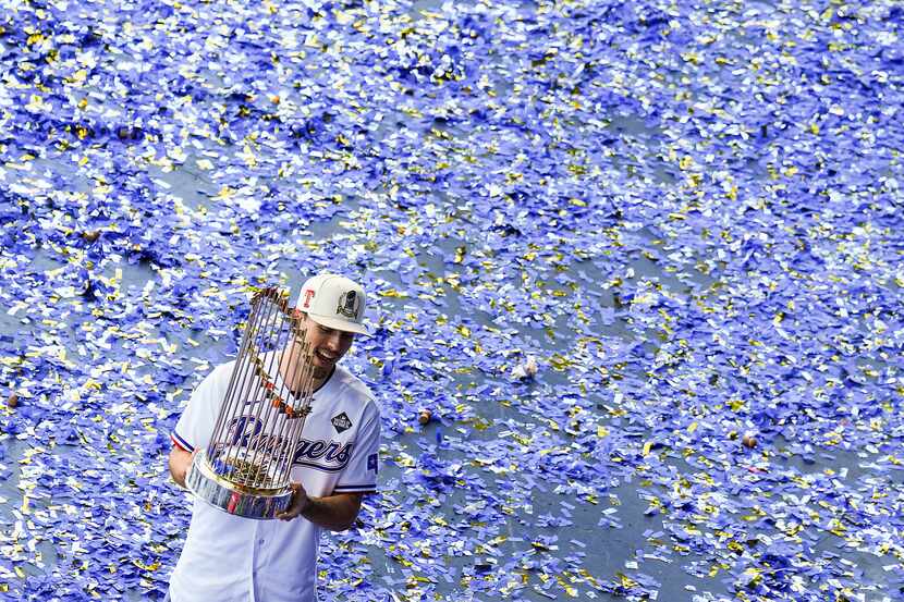 Evan Carter carries the Commissioner’s Trophy off of a confetti covered stage at the end of...