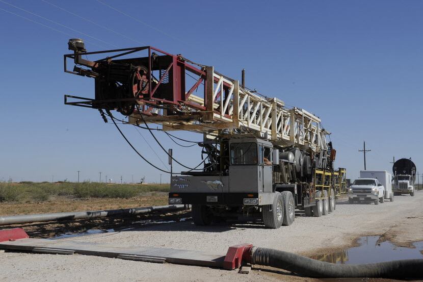 A drilling rig used for hydraulic fracturing is trucked across a water hose at a drill site...