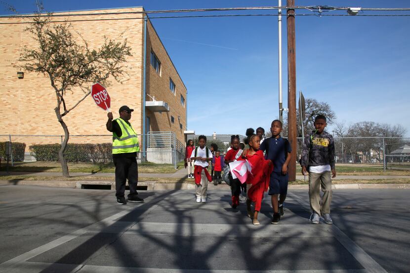 School crossing guard Derrick McMillon stops traffic on N. Washington as students leave J....