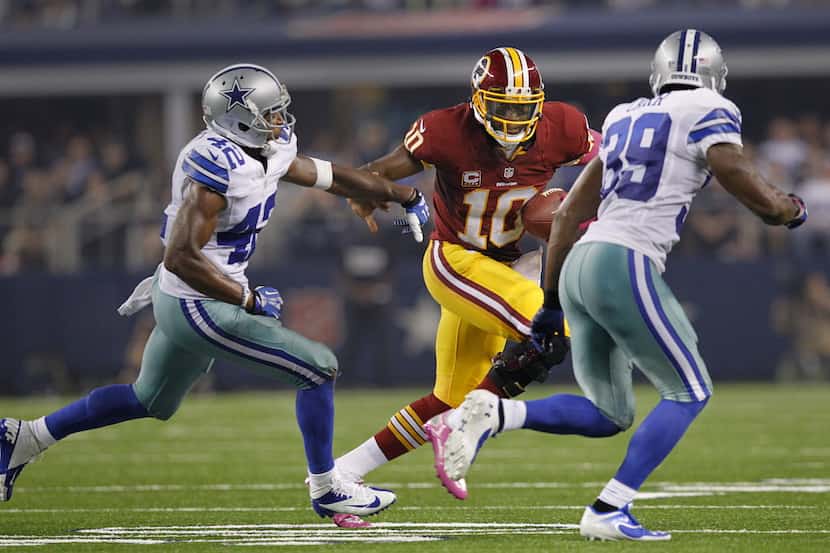 Washington Redskins quarterback Robert Griffin III (10) tries to escape the pass rush from...