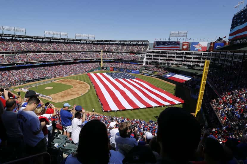 Texas Rangers fans celebrate as the national anthem is sung before a game between the Texas...