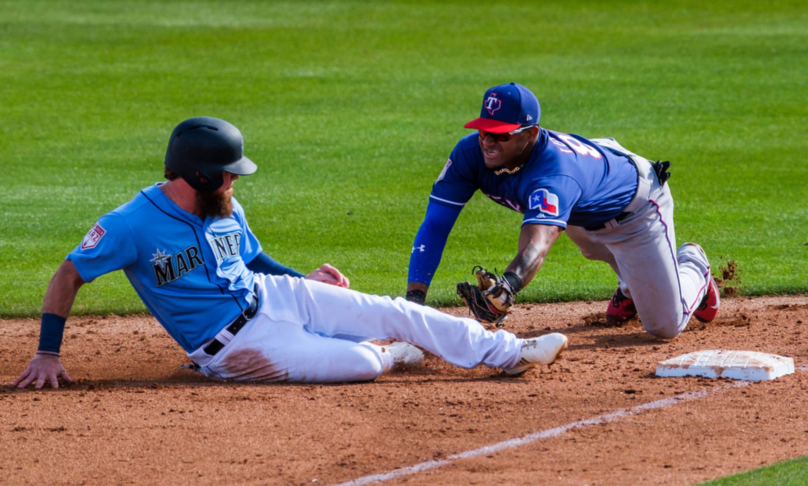 Texas Rangers infielder Andy Ibâñez dives to put the tag on Seattle Mariners outfielder...