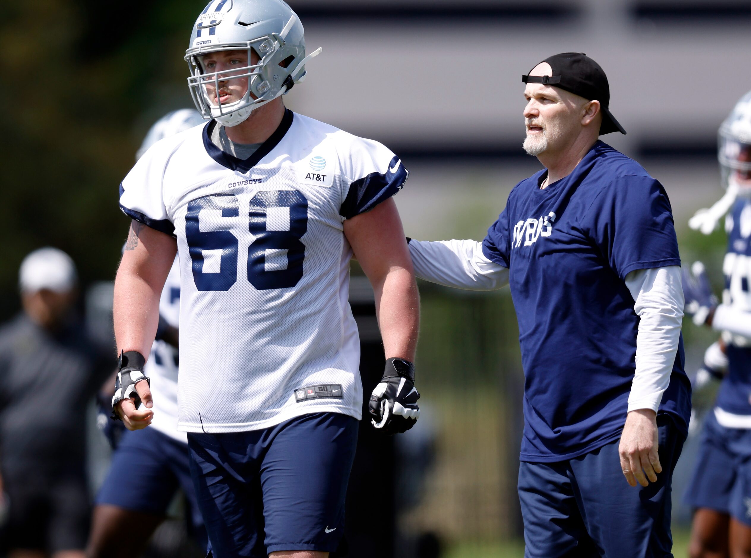 Dallas Cowboys defensive coordinator Dan Quinn gives rookie guard Matt Farniok (68) a slap...