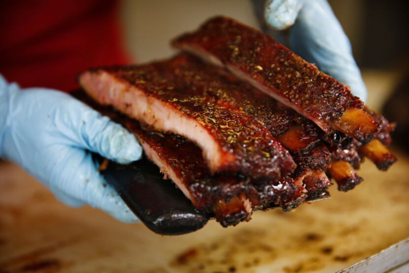 La Barbecue general manager Ali Clem cuts and serves ribs at the customer window of their...