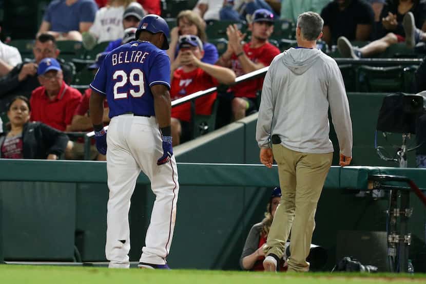 Texas Rangers' Adrian Beltre walks off the field with athletic trainer Kevin Harmon, right,...