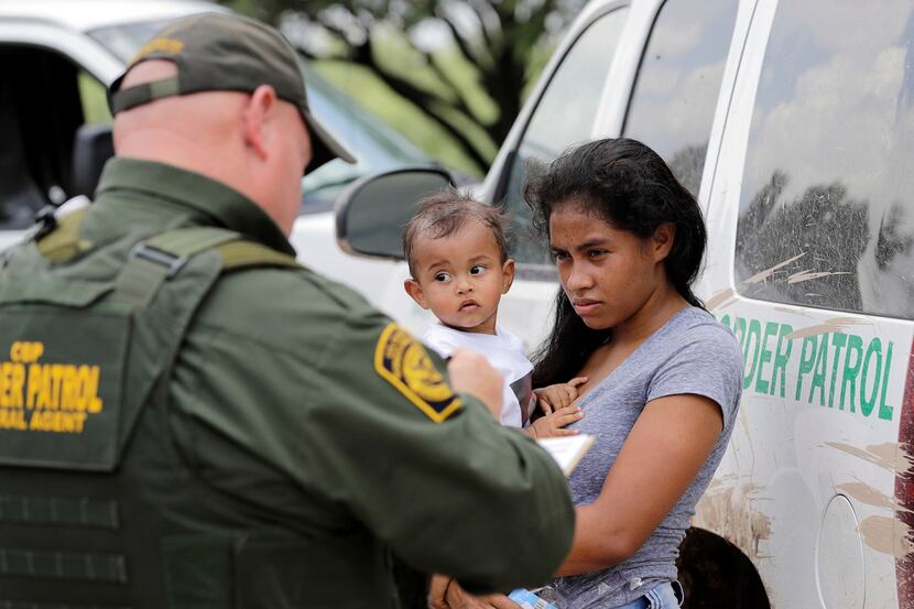 A mother migrating from Honduras holds her 1-year-old child as she surrenders to U.S. Border...