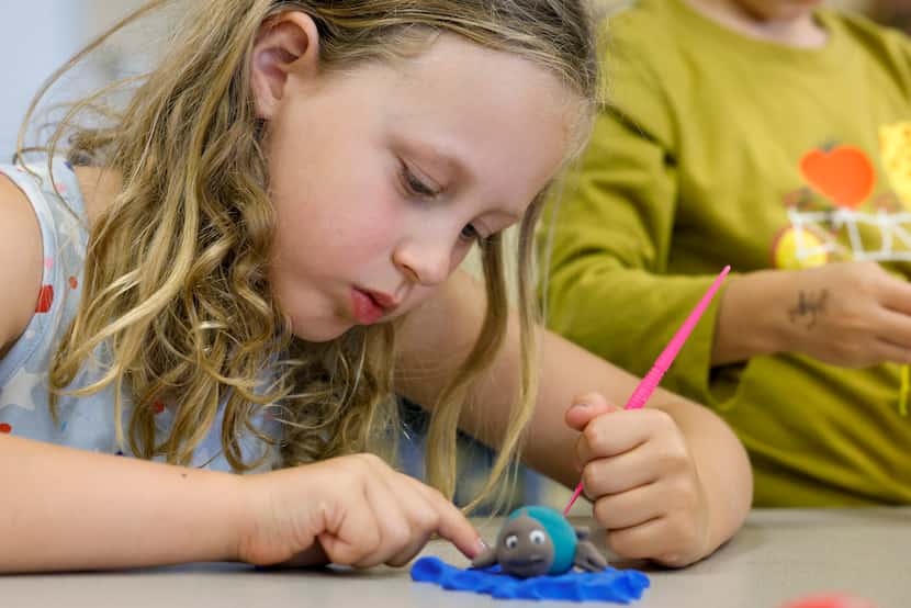 Lillian Moore, 6, adds detail to her sea turtle during an arts and crafts activity at Dallas...